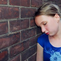 Sad young girl by wall